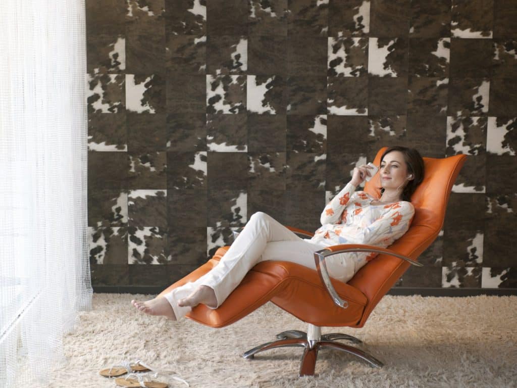 Vrouw ontspannen in een Jori Square relaxfauteuil in oranje leer