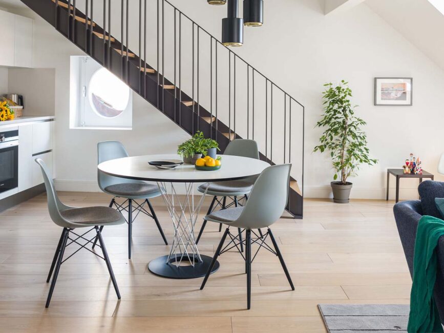 Ronde Vitra tafel met Eames stoelen onder een trap