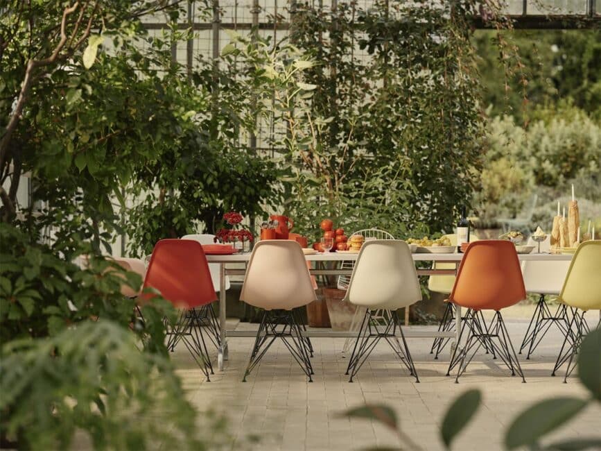 Vitra Eames Plastic stoelen in kleur aan een lange tafel tussen planten