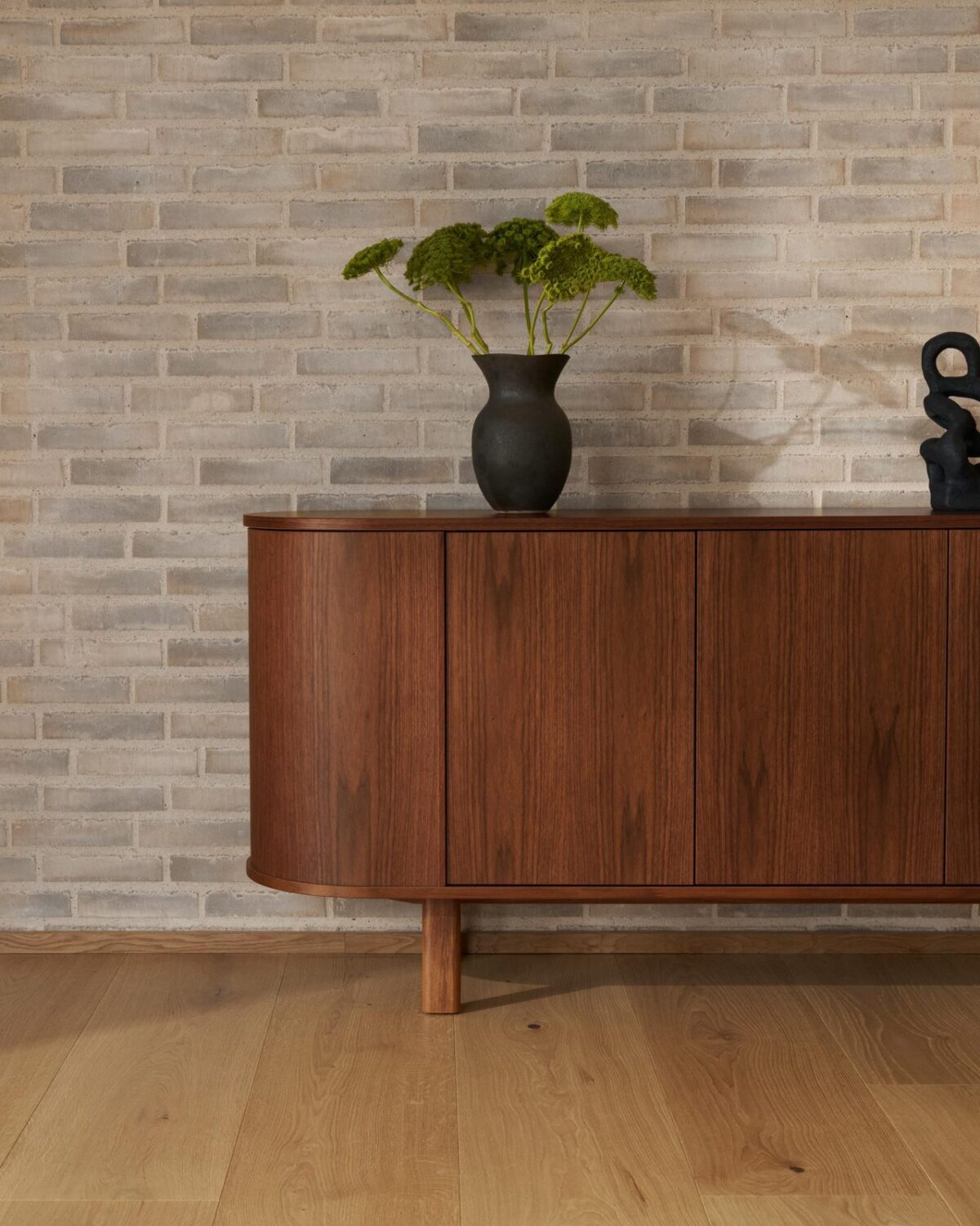 Skovby #543 walnoot dressoir tegen een bakstenen muur met vaas